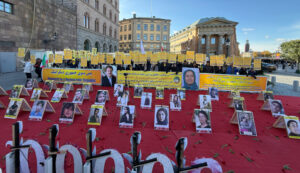 Mynttorget, Stockholm, 12 oktober 2024: Svensk- och exiliranier, sympatisörer till Iranska nationella motståndsrådet (NCRI), håller upp plakat under en demonstration som uppmanar Sverige att terrorstämpla revolutionsgardet och uttrycker solidaritet med politiska fångar i Iran som deltar i kampanjen ”Tisdagar mot avrättningar”.