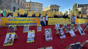 Mynttorget, Stockholm, 12 oktober 2024: Svensk- och exiliranier, sympatisörer till Iranska nationella motståndsrådet (NCRI), håller upp plakat under en demonstration som uppmanar Sverige att terrorstämpla revolutionsgardet och uttrycker solidaritet med politiska fångar i Iran som deltar i kampanjen ”Tisdagar mot avrättningar”.